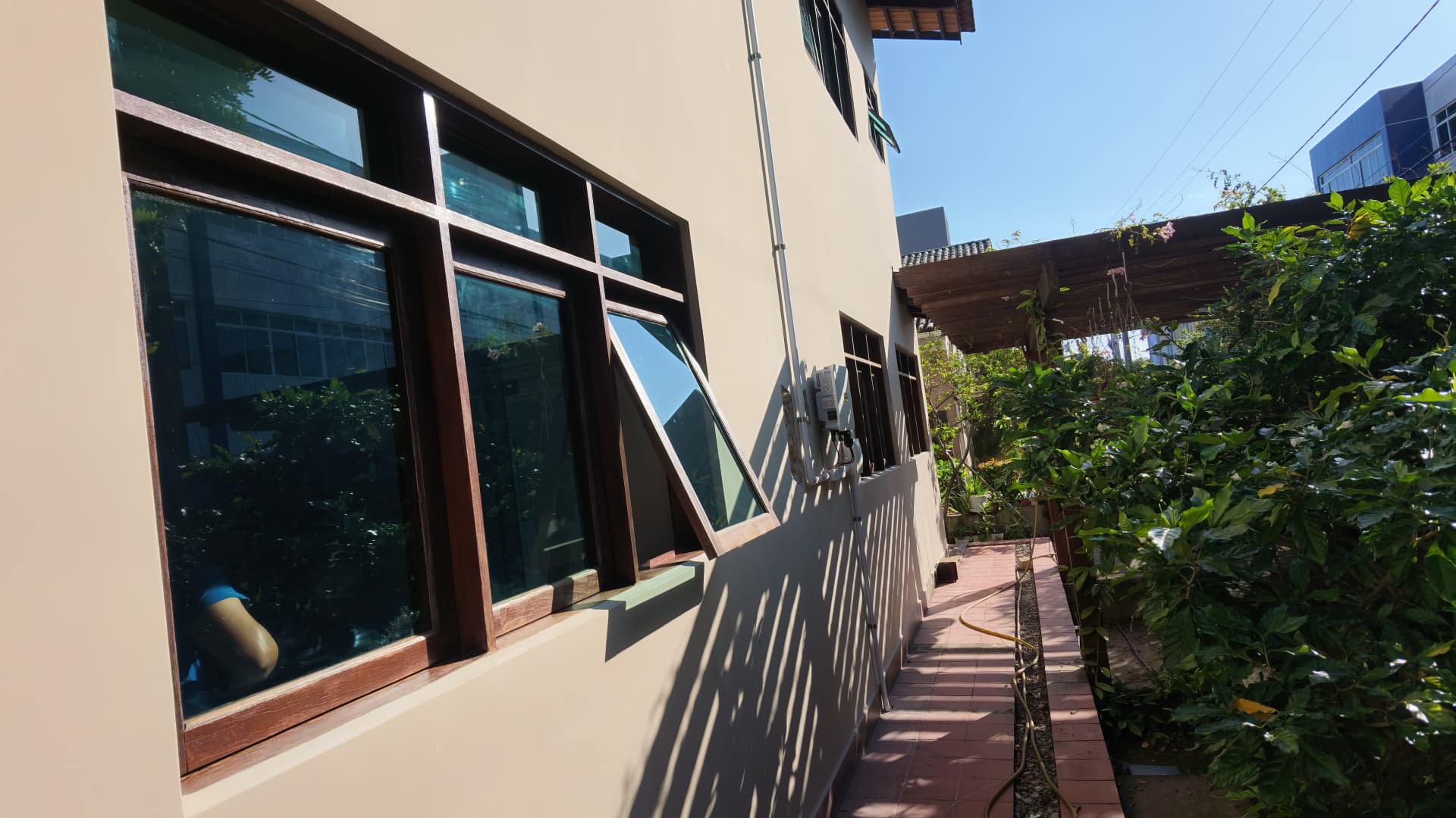 Vista externa das janelas de madeira com película Window Blue instalada em residência em João Pessoa