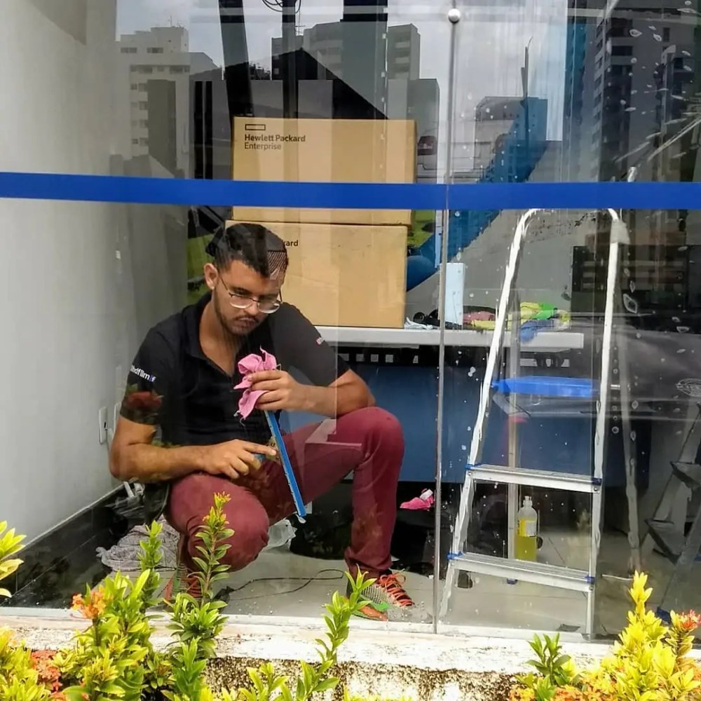 Aplicador instalando película de proteção UV em vitrine de loja